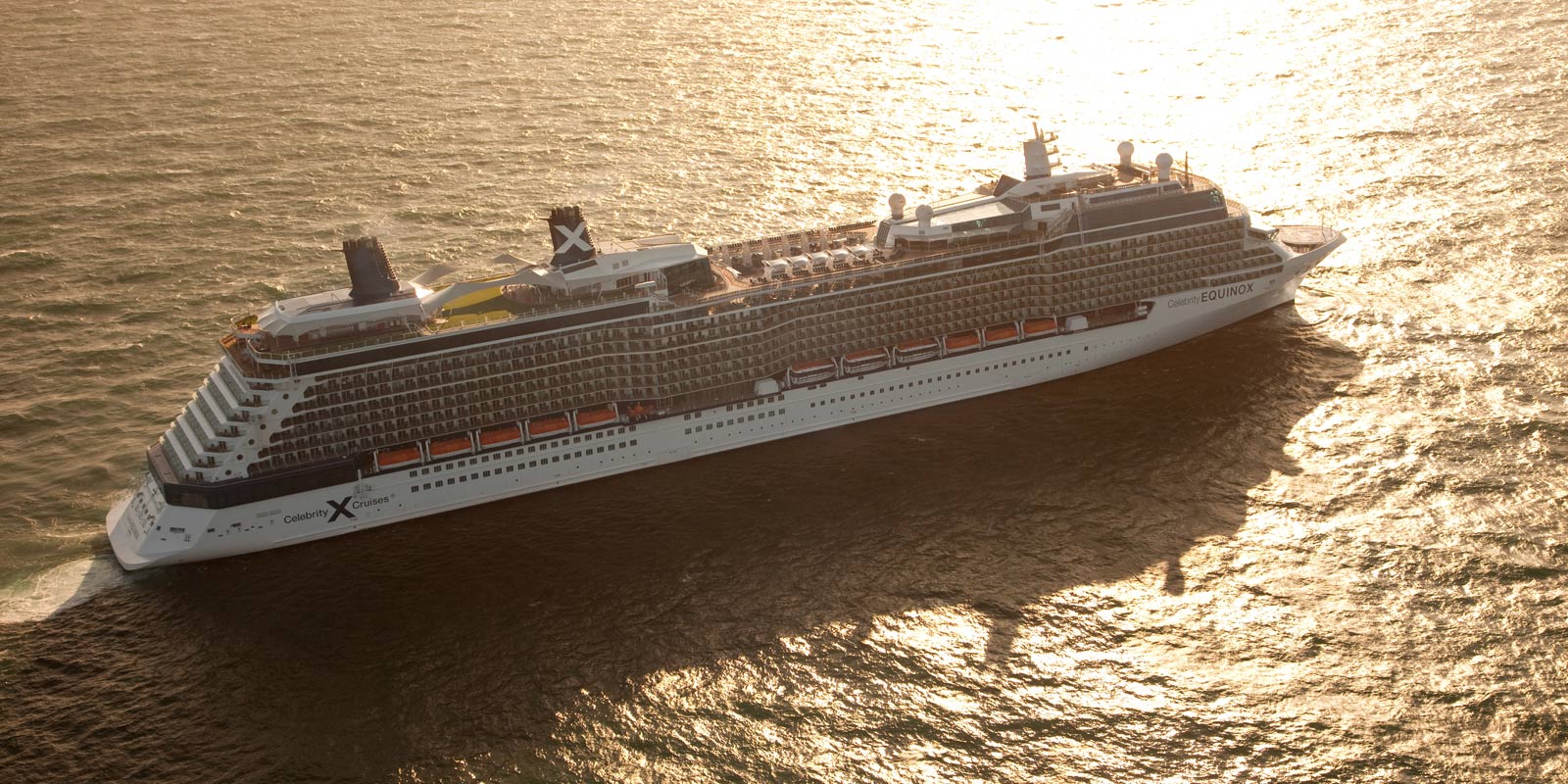 Kryssningsfartyget Celebrity Equinox ute till havs i solnedgång.