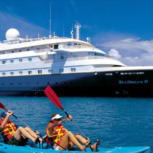 Kanotister framför fartyget SeaDream II från SeaDream Yacht Club.
