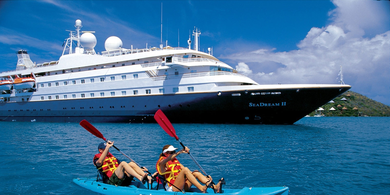 Kanotister framför fartyget SeaDream II från SeaDream Yacht Club.