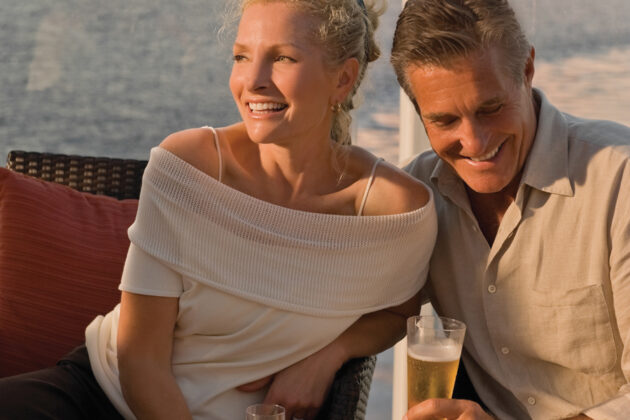 Par njuter av gott att dricka i solnedgången ombord på Celebrity Cruises fartyg.