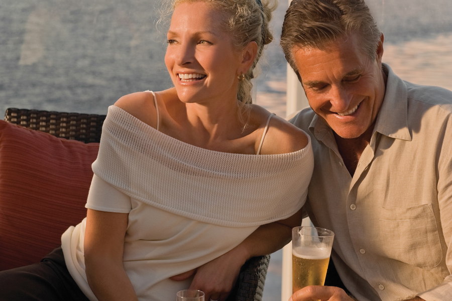 Par njuter av gott att dricka i solnedgången ombord på Celebrity Cruises fartyg.