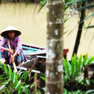 Kvinna i båt på Mekongfloden i Vietnam.