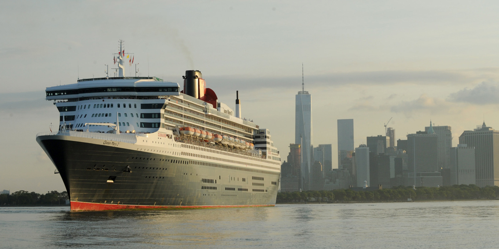 Cunards kryssningsfartyg Queen Mary 2 med New York, USA, skyline i bakgrunden.