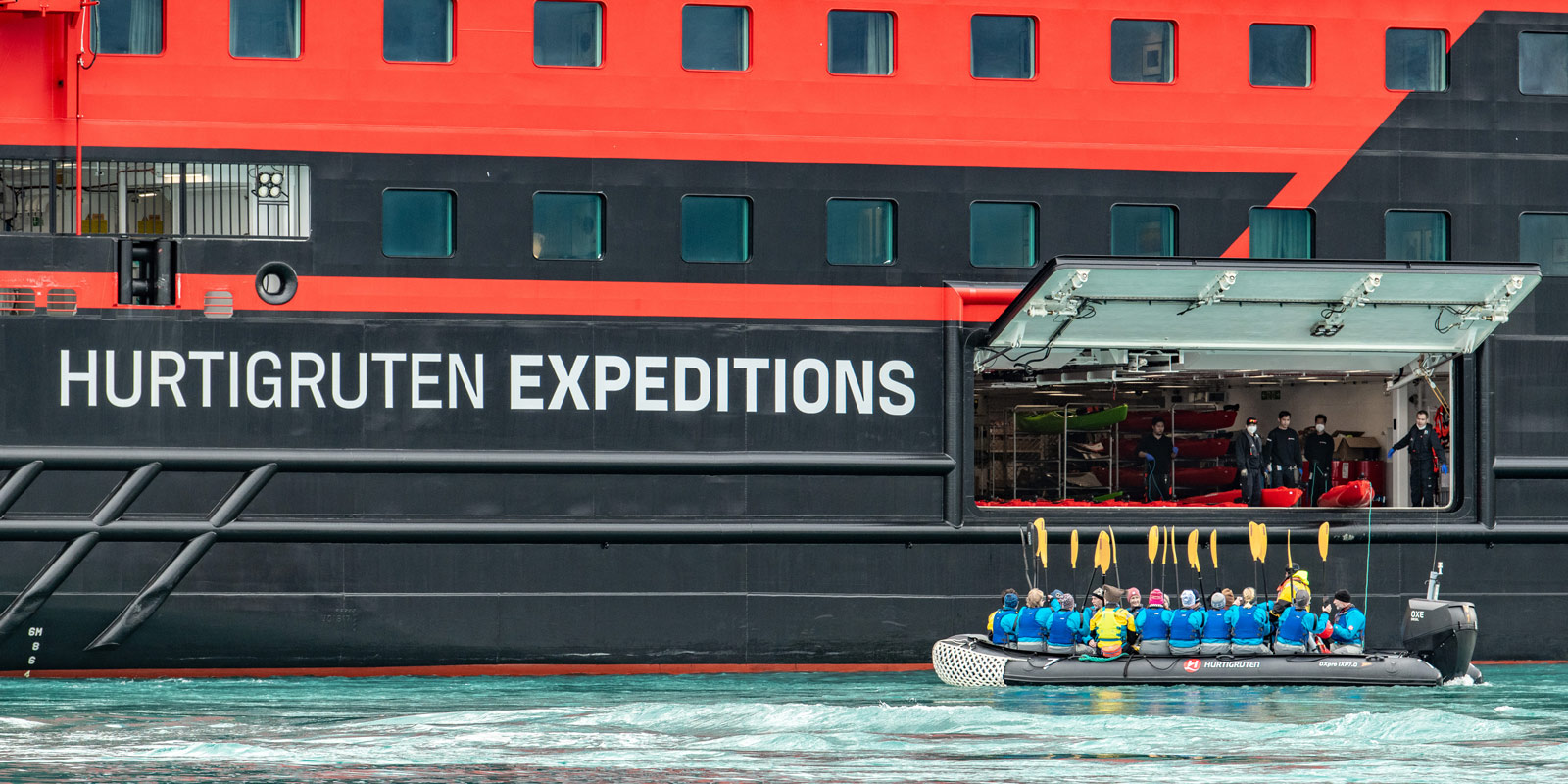 Gäster kliver ombord en zoodiak från HX Hurtigruten Expeditions fartyg.
