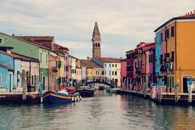 En kanal, båtar och färgstarka hus i Burano.