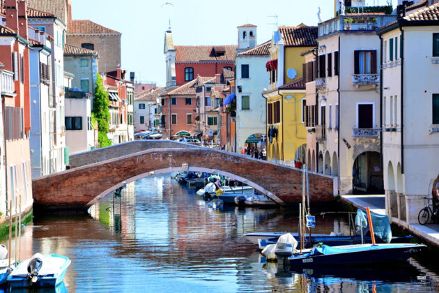 En skimrande kanal och bro i Chioggia.