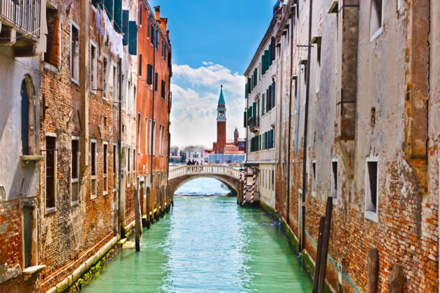 En smal kanal i Venedig med turkosskimrande vatten.